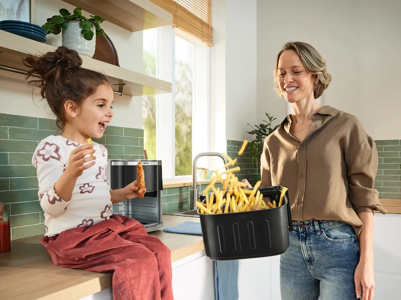 Dievča sa teší, ako mama premiešava hranolky vo fritéze Bosch MAF671C0 Serie 6