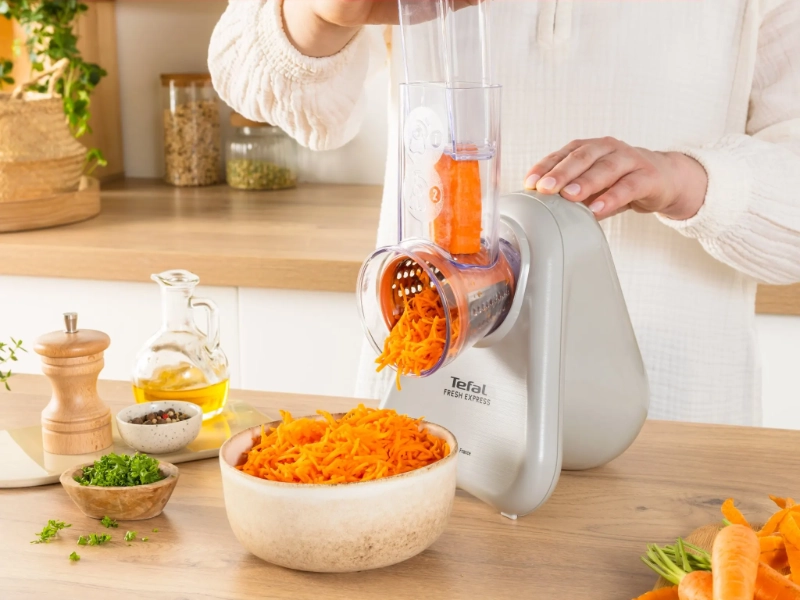 Žena str&uacute;ha mrkvu na str&uacute;hadle Tefal DN853BE0 Fresh Express do misky